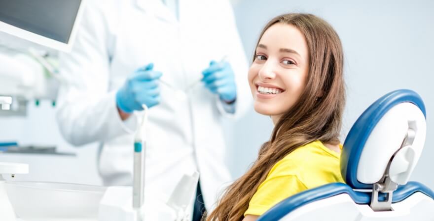 Woman in yellow blouse smiling in treatment chair at endodontic office in Livingston
