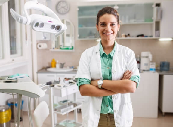 Smiling dentist in white lab coat standing with arms crossed