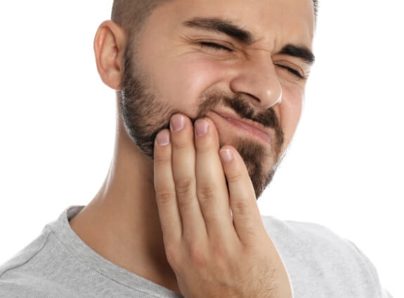 Man wincing in pain and holding his cheek